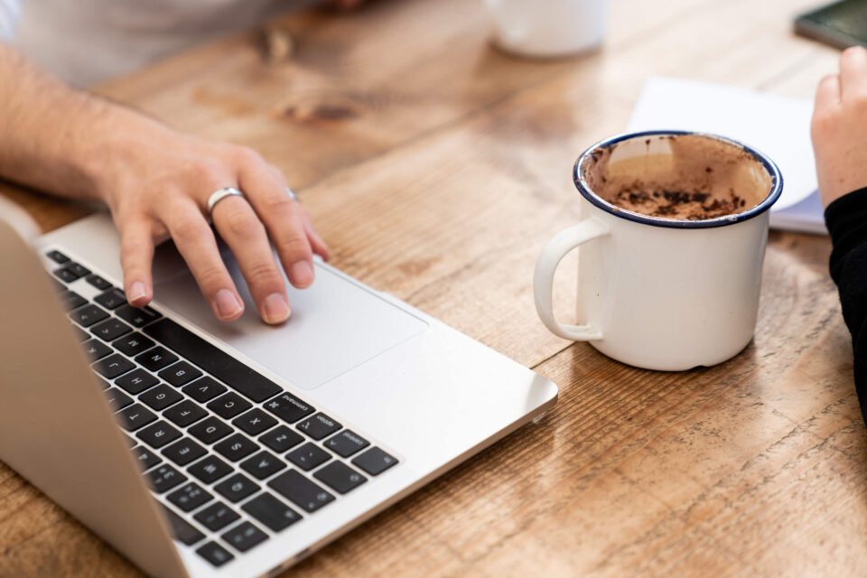 macbook on a wooden desk with a hot coffee drink