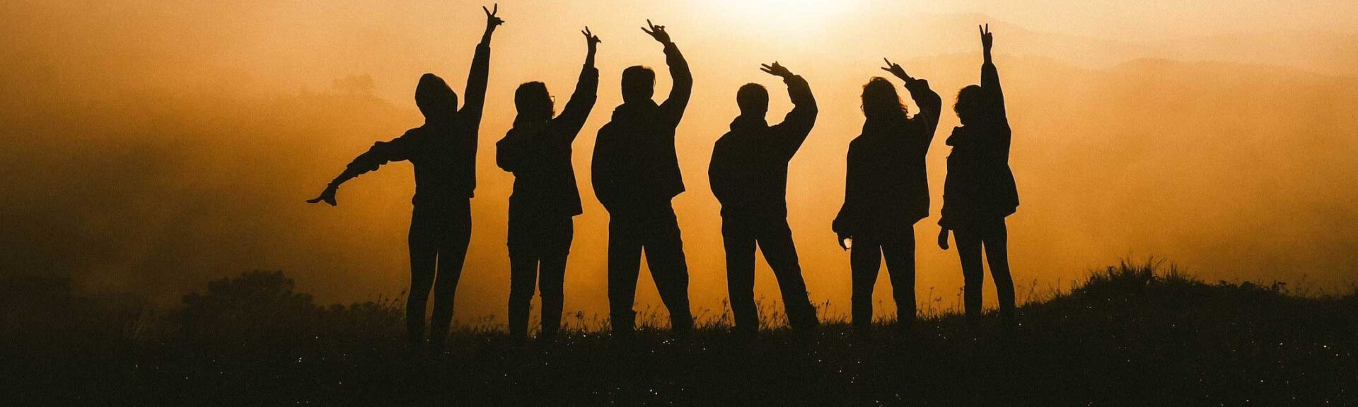 silhouettes of a group of people in front of a setting sun